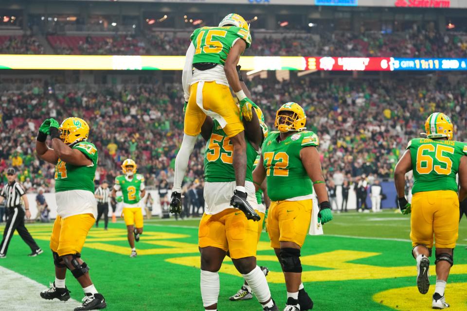 Oregon Ducks wide receiver Tez Johnson (15) celebrates scoring a touchdown with defensive lineman Tevita Pome'e (59) during the second half against the Liberty Flames in the 2024 Fiesta Bowl at State Farm Stadium.