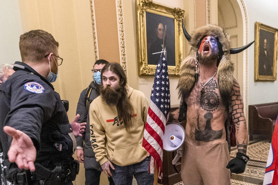 FILE - In this Jan. 6, 2021 file photo, supporters of President Donald Trump, including Jacob Chansley, right with fur hat, are confronted by U.S. Capitol Police officers outside the Senate Chamber inside the Capitol in Washington. Many of those who stormed the Capitol on Jan. 6 cited falsehoods about the election, and now some of them are hoping their gullibility helps them in court. Albert Watkins, the St. Louis attorney representing Chansley, the so-called QAnon shaman, likened the process to brainwashing, or falling into the clutches of a cult. Repeated exposure to falsehood and incendiary rhetoric, Watkins said, ultimately overwhelmed his client's ability to discern reality. (AP Photo/Manuel Balce Ceneta, File)