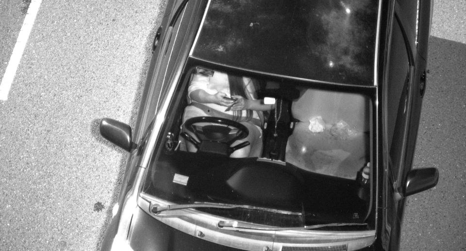 An aerial shot of a woman in a car using her mobile whilst driving. 