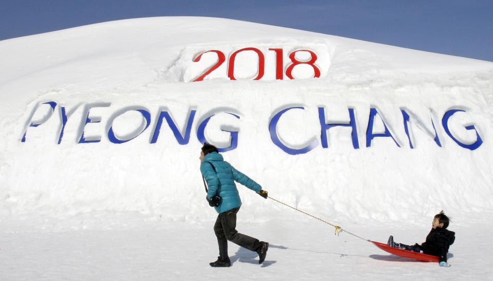 FILE - In this Feb. 19, 2011 file photo, a South Korean father pulls his son on a sled in front of a sign promoting the Pyeongchang 2018 Winter Olympics in Pyeongchang, east of Seoul, South Korea. The people of Pyeongchang can confidently promise two things when they host the Olympics: it’ll be cold, and there’ll be no concerns about snow. While a warm spell has created challenging conditions for the skiers and snowboarders competing in the mountains above Sochi at the 2014 edition, there’s been heavy dumps of snow in the region that will host the next Winter Games in 2018. (AP Photo/ Lee Jin-man, File)