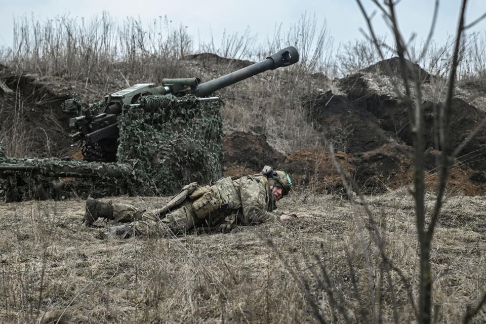 A Ukrainian serviceman drops to the ground to take cover during shelling next to a 105mm howitzer near the city of Bakhmut (AFP via Getty Images)