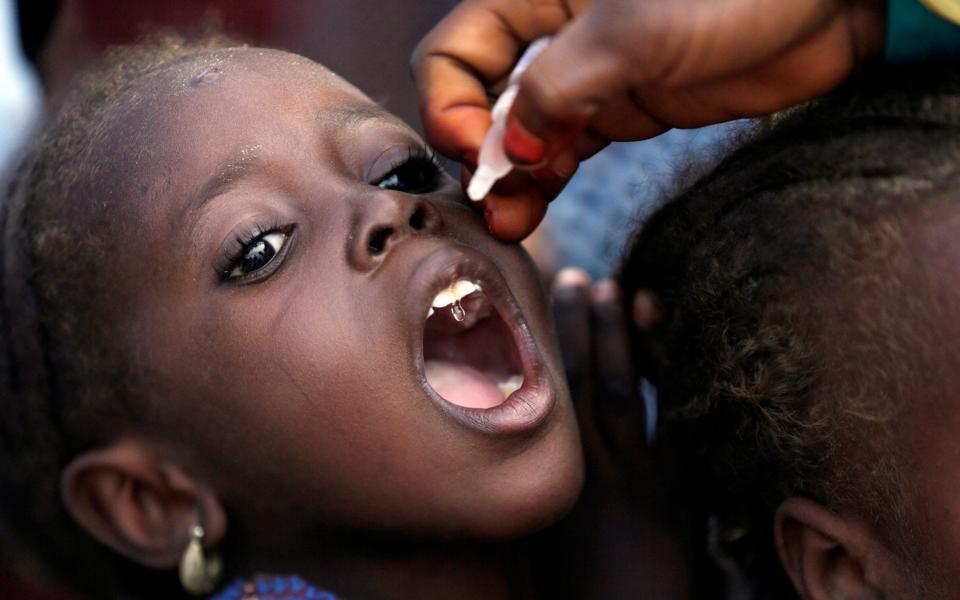 A health official giving the polio vaccine to a child in a camp for displaced people in Maiduguri, Nigeria - AP