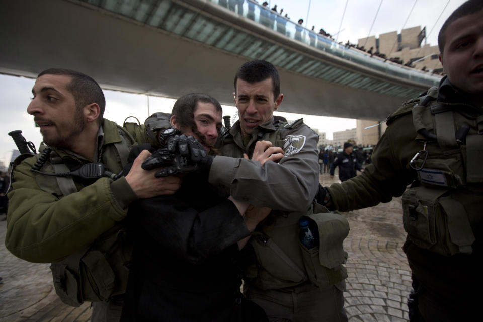 Israeli border police officers detain an ultra-Orthodox Jewish man during a demonstration in Jerusalem, Thursday, Feb. 6, 2014. Israeli police said thousands of ultra-Orthodox Jews are blocking highways across the country to protest plans to enlist them into the military. (AP Photo/Sebastian Scheiner)