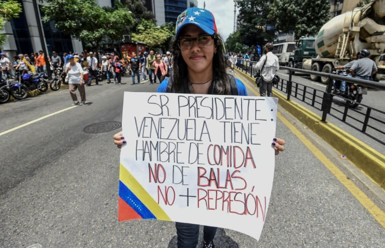 A Venezuelan opposition activist holds a placard reading, "Mr. President, Venezuela is Hungry for food not for bullets. No more repression"