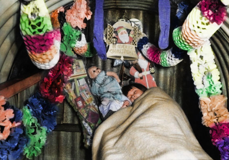 <p>A child sleeps cuddles up with her doll in an Anderson air raid shelter full of Christmas decorations. (MediaDrumWorld) </p>