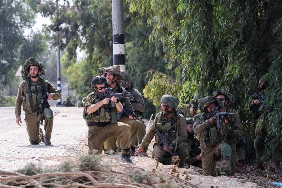 Israeli soldiers take up position in Kfar Aza, in the south of Israel, bordering Gaza Strip on Tuesday (AFP via Getty Images)