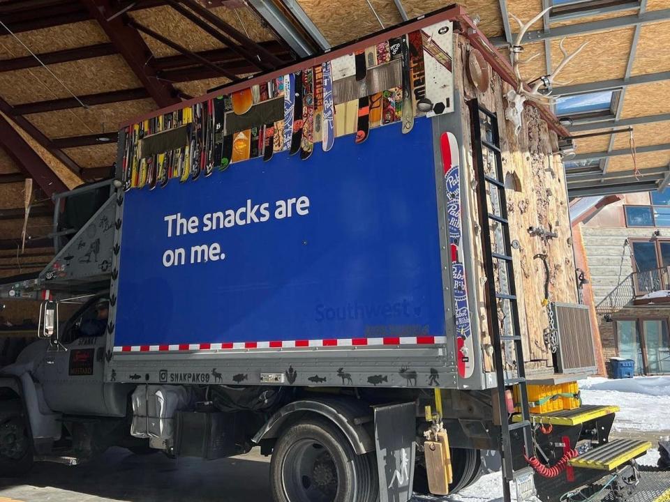 The sides of the aircraft catering truck are lines with snowboards, while the back is covered in logs.