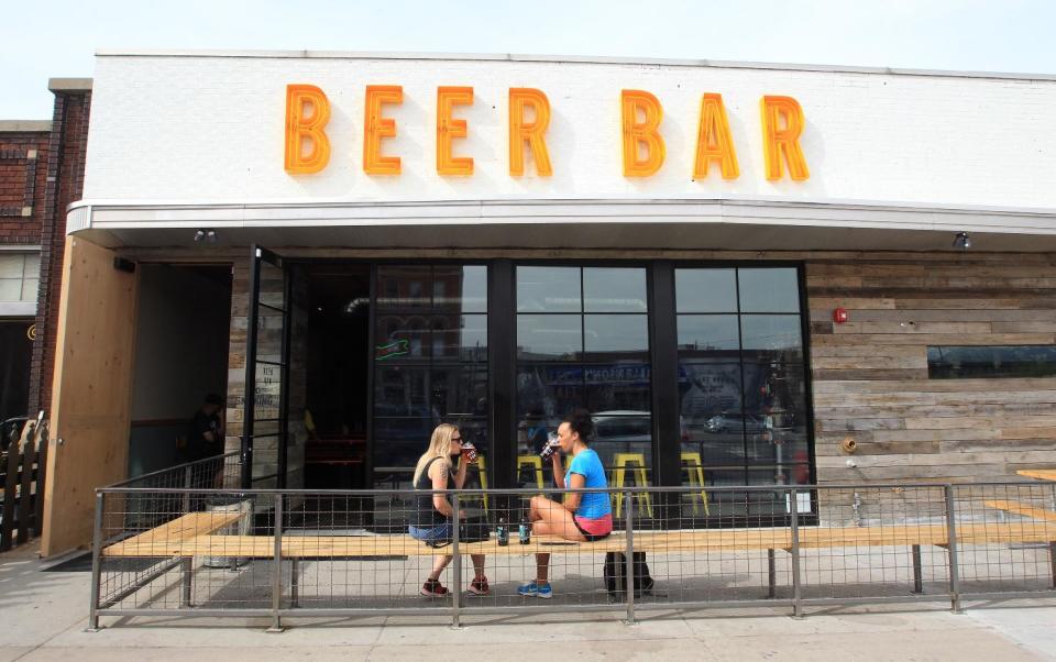 In this April 21, 2014 photo, Noelle Fitzgerald, left, and Ashly Burton drink beer at Beer Bar in Salt Lake City. Actor Ty Burrell, who plays bumbling dad Phil Dunphy on ABC's “Modern Family,” just opened Beer Bar, a beer garden-like eatery that serves 150 beers paired up with an array of house-made bratwursts, local breads and Belgian fries. The restaurant sports long tables and benches with high ceilings to evoke that Bavarian beer hall feel. (AP Photo/Rick Bowmer)