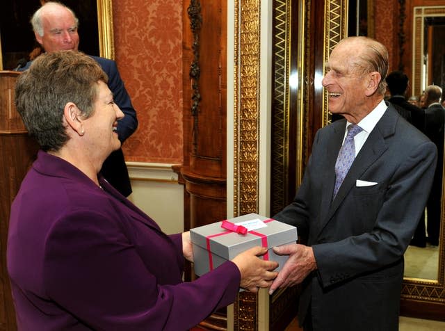 The Duke of Edinburgh receives a pair of ear defenders given to him as a birthday present from Jackie Ballard, chief executive of Action on Hearing Loss charity during a reception for the charity at Buckingham Palace in central London 