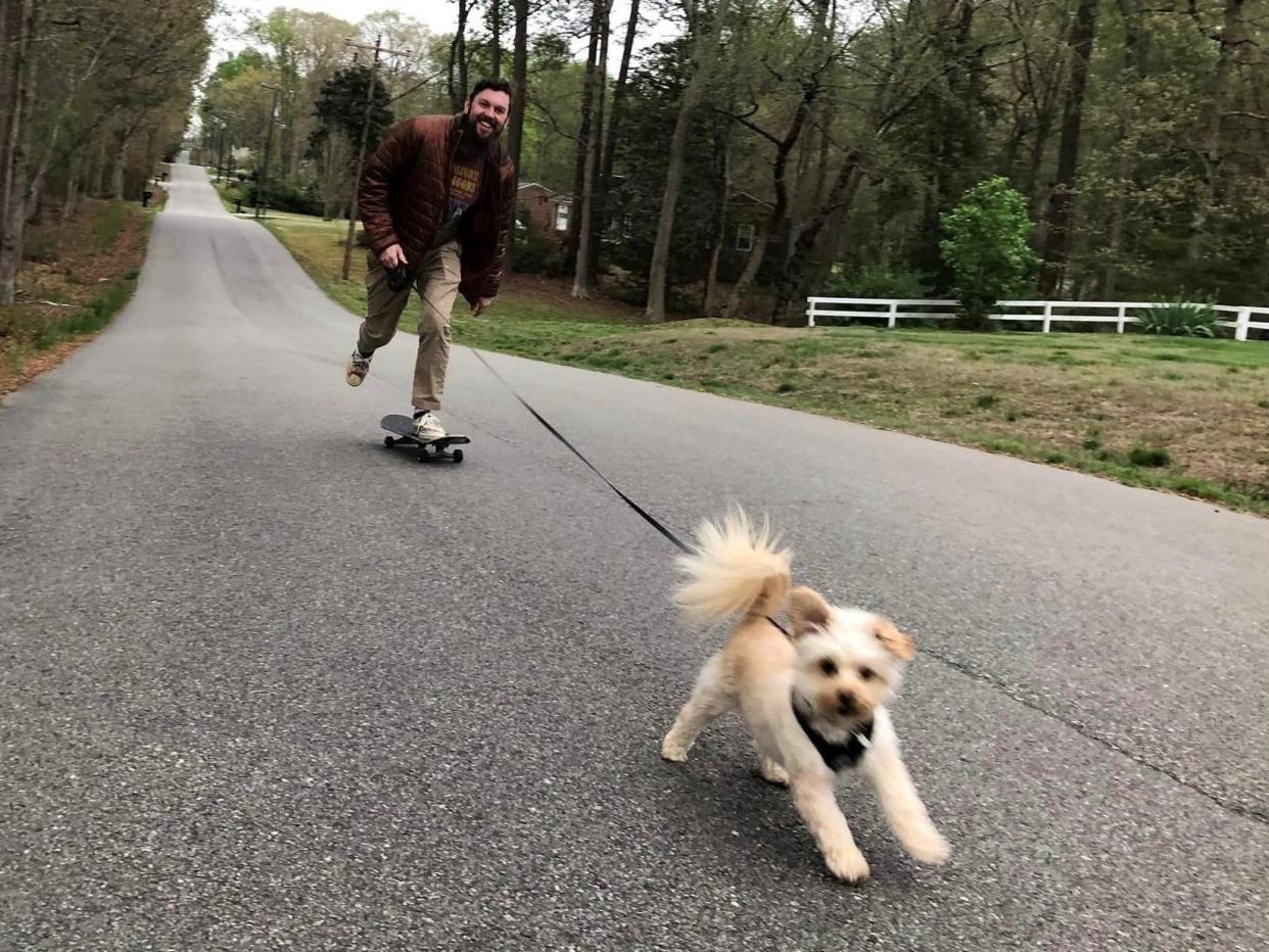 Chihuahua/poodle mix Waffles runs while human companion Orry McCabe skateboards in Chester, Va. on April 8, 2023.