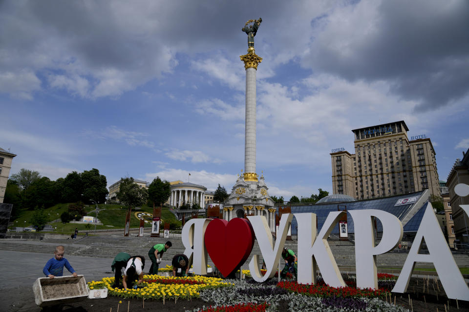 People plant flowers in Independence Square, downtown Kyiv, Ukraine, Monday, May 23, 2022. (AP Photo/Natacha Pisarenko)