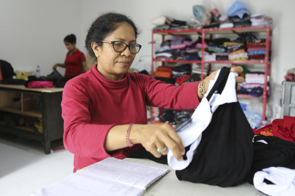 Ni Luh Erniati, who lost her husband in a 2002 Bali bombing, folds clothing as she runs her tailoring business in Denpasar, Bali, Indonesia, on Oct. 4, 2022. Erniati's husband was one of 202 people killed when a car bomb outside Sari Club and a suicide bombing at nearby Paddy's Pub went off in Kuta, Bali, on Oct. 12, 2002. (AP Photo/Firdia Lisnawati)