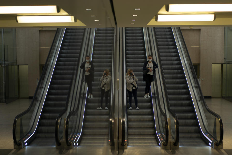 Two women, wearing masks to protect against the spread of coronavirus, take escalators at North train station in Brussels, Wednesday, Aug. 26, 2020. Protective face masks are mandatory in Brussels in all public spaces. (AP Photo/Francisco Seco)