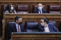 Prime Minister Pedro Sanchez, left and 2nd deputy Prime Minister Pablo Iglesias talk during a parliamentary session in Madrid, Spain, Wednesday Oct. 21, 2020. Spanish Prime Minister Pedro Sanchez faces a no confidence vote in Parliament put forth by the far right opposition party VOX. (AP Photo/Manu Fernandez, Pool)