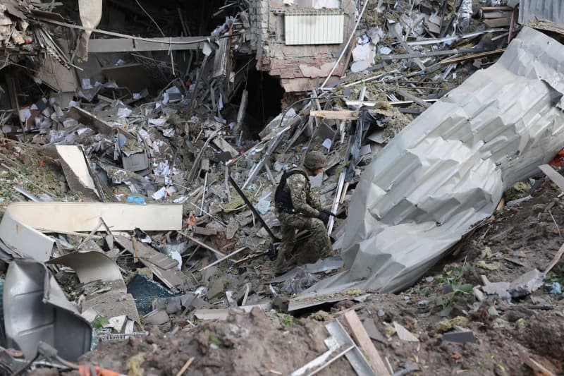 A law enforcement officer examines a crater in an office building that was destroyed by a Russian missile strike in the center of Kharkiv in northeastern Ukraine. -/Ukrinform/dpa