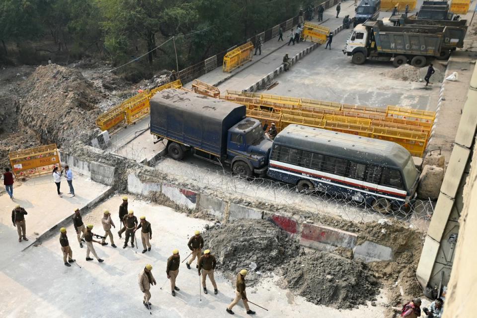 Police personnel stand guard next to a barrier and vehicles blocking a road to prevent farmers protesting to demand minimum crop prices from marching towards India’s capital at the Delhi-Uttar Pradesh border in Ghazipur (AFP via Getty Images)