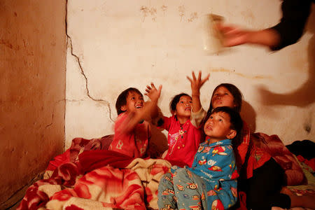 Refugee children who fled with their family fighting in neighbouring Myanmar reach for a mobile phone in the house of a relative in the village of Baiyan near Nansan in the Yunan province, China, March 11, 2017. REUTERS/Thomas Peter