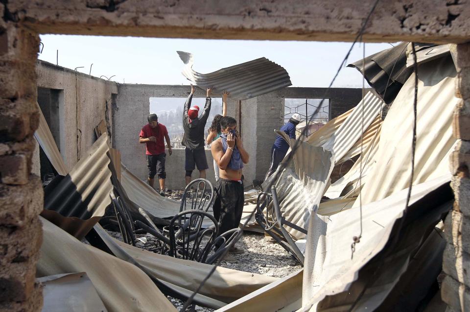 Residents work to remove the remains of a house after a forest fire burned several neighbourhoods in the hills in Valparaiso city