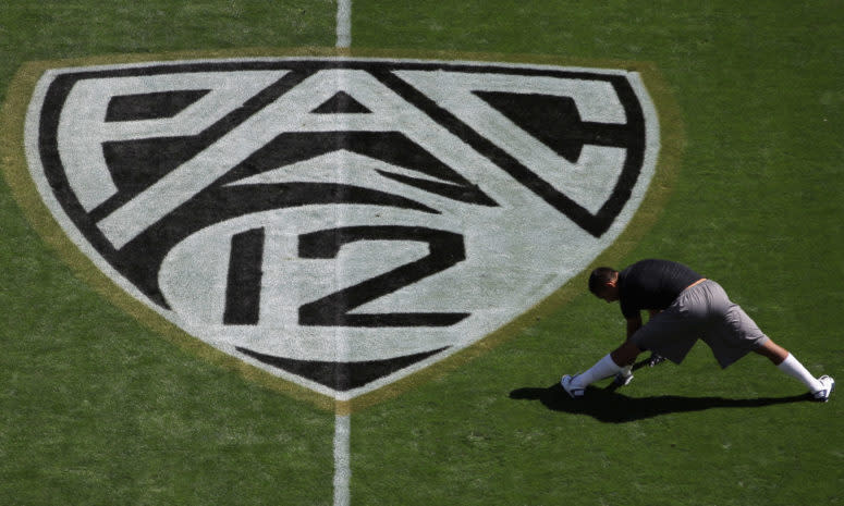 A member of Cals football team stretching next to a Pac-12 football logo.