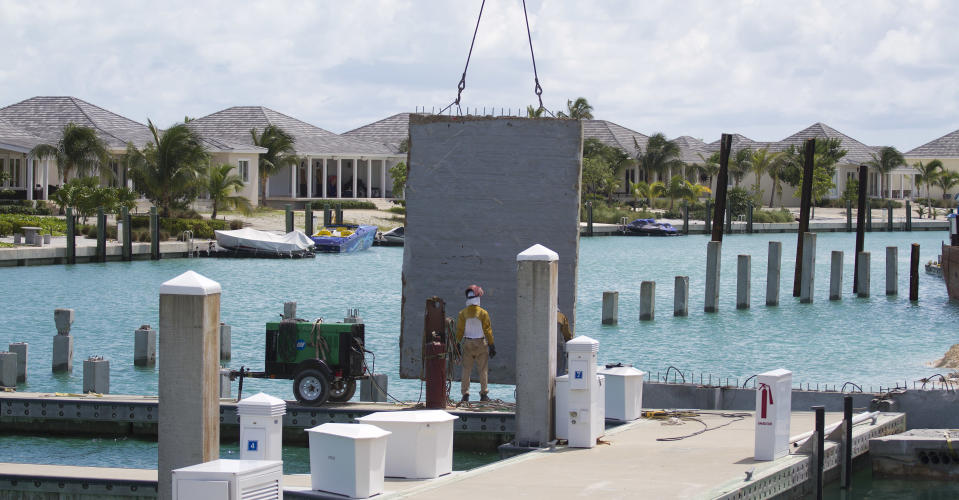 In this Sept. 11, 2013 photo, a construction worker stands on the expanded dock for Resorts World Bimini resort, in Bimini, Bahamas. Changes are coming fast to Bimini. Malaysia-based Genting Group is spending at least $300 million on Resorts World Bimini, quickly becoming the largest employer in the cluster of islands and creating sharp new demand for housing, but there is also an uneasiness about what may happen to the delicate ecosystem and rough-around-the-edges atmosphere that are key to Bimini’s identity as a sport fishing capital of the world. (AP Photo/J Pat Carter)