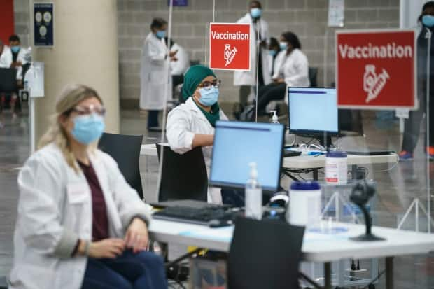 Health-care workers wait for patients at a COVID-19 vaccination clinic in Montreal's Olympic Stadium on Tuesday.