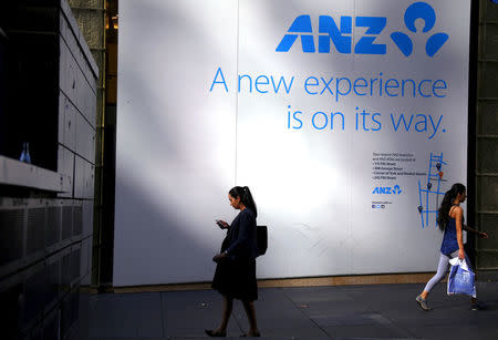 FILE PHOTO - A woman looks at her iPhone as she walks past a sign announcing a new branch of the Australia and New Zealand Banking Group Ltd (ANZ) in central Sydney, Australia, April 27, 2016. REUTERS/David Gray/File Photo