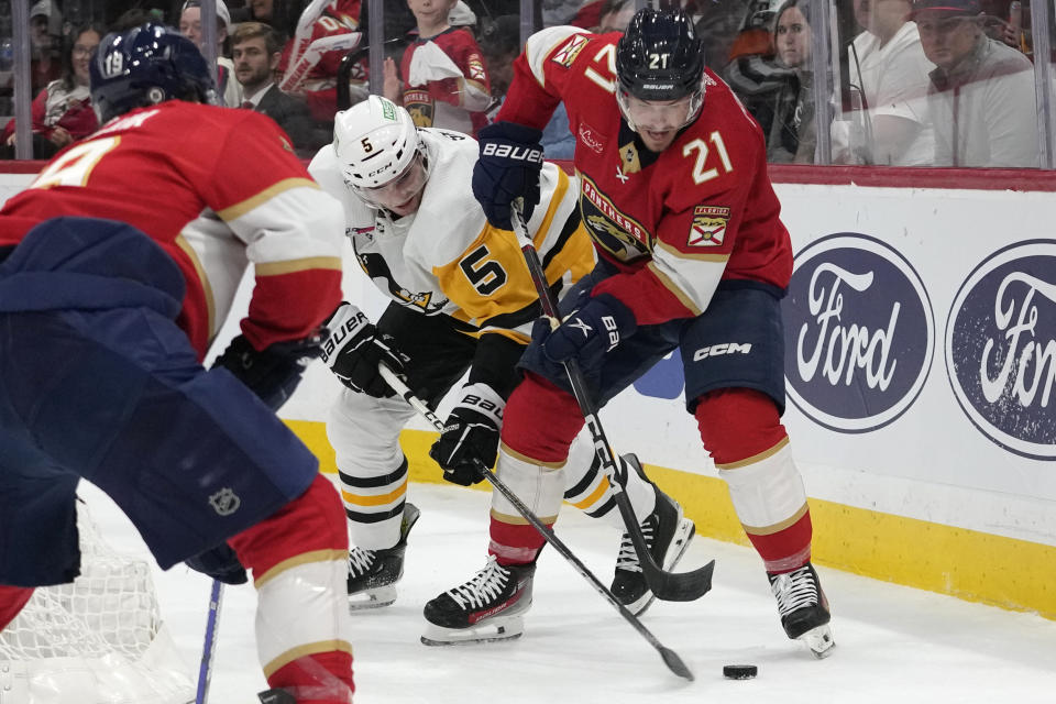 Pittsburgh Penguins defenseman Ryan Shea (5) and Florida Panthers center Nick Cousins (21) go for the puck during the second period of an NHL hockey game, Friday, Dec. 8, 2023, in Sunrise, Fla. (AP Photo/Lynne Sladky)