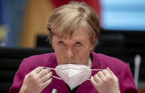 German Chancellor Angela Merkel takes off her mask at the beginning of the Federal Cabinet meeting at the Chancellery in Berlin, Germany, Wednesday, March 3, 2021. (Michael Kappeler/Pool via AP)