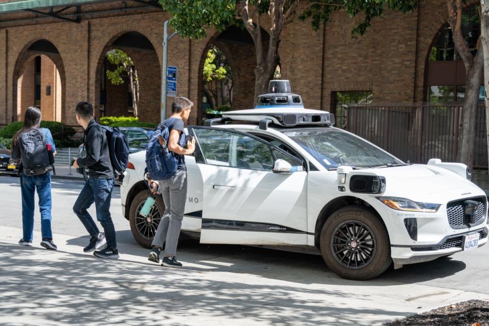 Pedestrians exit a Waymo self-driving car in front of Google's headquarters in San Francisco.<p>Smith Collection/Gado/Getty Images</p>