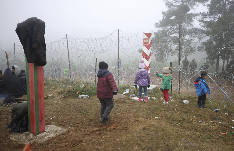 Migrants from the Middle East and elsewhere stand near the barbed wire gathering at the Belarus-Poland border near Grodno, Belarus, Thursday, Nov. 11, 2021. The European Union has accused Belarus' authoritarian President Alexander Lukashenko of encouraging illegal border crossings as a "hybrid attack" to retaliate against EU sanctions on his government for its crackdown on internal dissent after Lukashenko's disputed 2020 reelection. (Leonid Shcheglov/BelTA via AP)