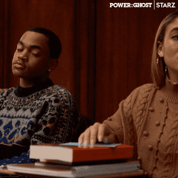 Tariq and Paige, both wearing sweaters, sitting at a desk and smiling