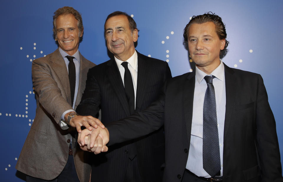 From left, Alessandro Benetton, chairman of the Cortina 2021 Foundation, Giuseppe Sala, mayor of Milan, and Gianpietro Ghedina, mayor of Cortina d'Ampezzo, pose for photographers during a press presentation of the Cortina 2021 ski world championships, in Milan, Italy, Thursday, Nov. 15, 2018. Enjoying its status of the leading contender to host the 2026 Winter Olympics, the Milan-Cortina d'Ampezzo bid has received another boost with a funding promise from the Italian government. (AP Photo/Luca Bruno)