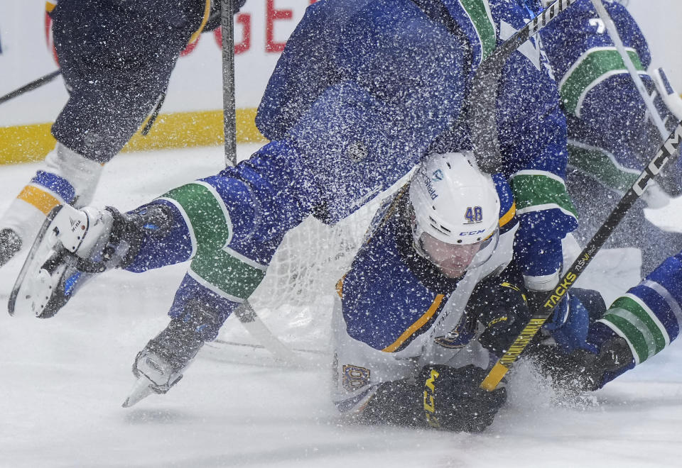 St. Louis Blues' Scott Perunovich (48) collides with Vancouver Canucks' Noah Juulsen, left, during the second period of an NHL hockey game Wednesday, Jan. 24, 2024, in Vancouver, British Columbia. (Darryl Dyck/The Canadian Press via AP)