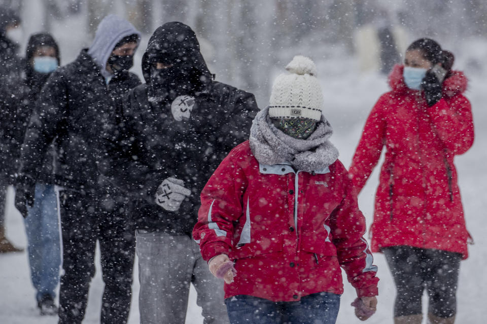 People walk during a heavy snowfall in Rivas Vaciamadrid, Spain, Saturday, Jan. 9, 2021. An unusual and persistent blizzard has blanketed large parts of Spain with snow, freezing traffic and leaving thousands trapped in cars or in train stations and airports that had suspended all services as the snow kept falling on Saturday. The capital, Madrid, and other parts of central Spain activated for the first time its red weather alert, its highest, and called in the military to rescue people from cars vehicles trapped in everything from small roads to the city's major thoroughfares. (AP Photo/Manu Fernandez)