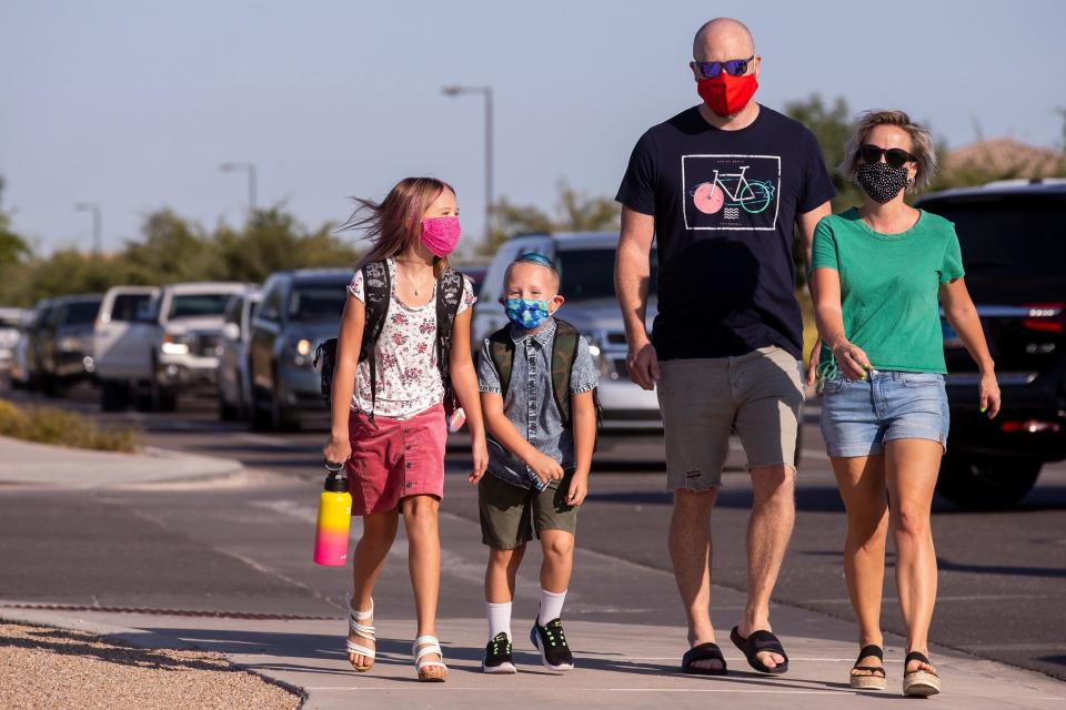 Brian and Kelly Harris walk with their children, Avery, 9, and Jack, 5, on the first day of school on Aug. 17, 2020, at Faith Mather Sossaman Elementary School in Queen Creek, Ariz.
