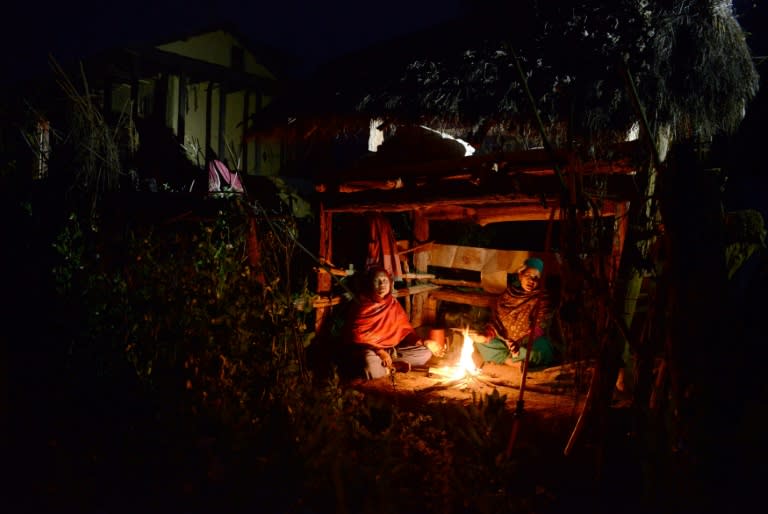 Nepalese women Pabitra Giri (L) and Yum Kumari Giri sit by a fire as they live in a Chhaupadi hut during their menstruation period, in Surkhet District, some 520 km west of Kathmandu