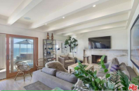 <p>The living room is modern yet cozy with its beamed-ceilings and fireplace. (Trulia.com) </p>