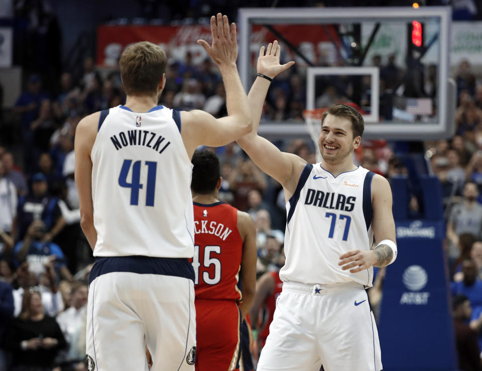Dallas Mavericks' Dirk Nowitzki (41) and Luka Doncic (77) celebrate after Nowitzki scored a basket against the New Orleans Pelicans in the first half of an NBA basketball game in Dallas, Monday, March 18, 2019. The basket placed Nowitzki as the sixth all-time league leading scorer surpassing Wilt Chamberlain. (AP Photo/Tony Gutierrez)