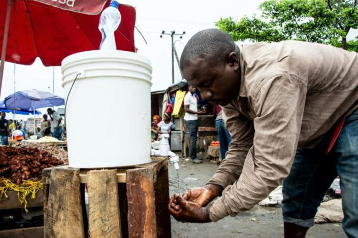 A man washes his hands with chlorinated water at Mabibo market in Dar es Salaam (AFP Photo/Ericky BONIPHACE)
