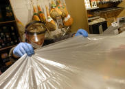 An employee of a supermarket protects food before proceeding with sanitization operations at closure, in Rome, Sunday, March 22, 2020. For most people, the new coronavirus causes only mild or moderate symptoms. For some it can cause more severe illness, especially in older adults and people with existing health problems. (Mauro Scrobogna/LaPresse via AP)