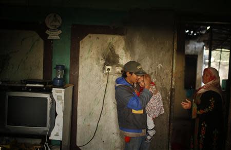 A Palestinian boy carries his sister inside their family's house in the northern Gaza Strip March 20, 2014. REUTERS/Mohammed Salem