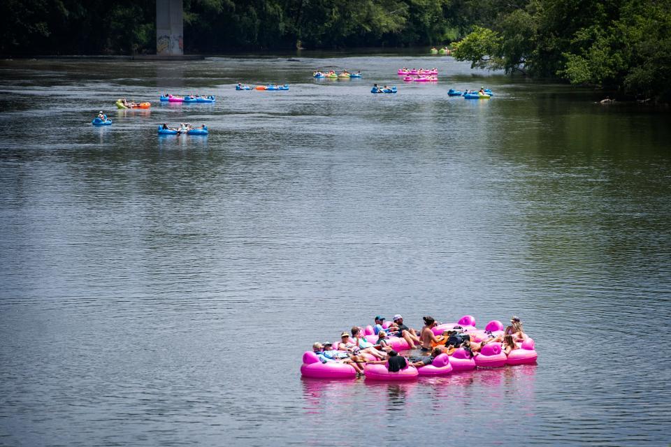 Several groups of people float toward the Craven Street Bridge on the French Broad River in rented tubes on July 17, 2020. 