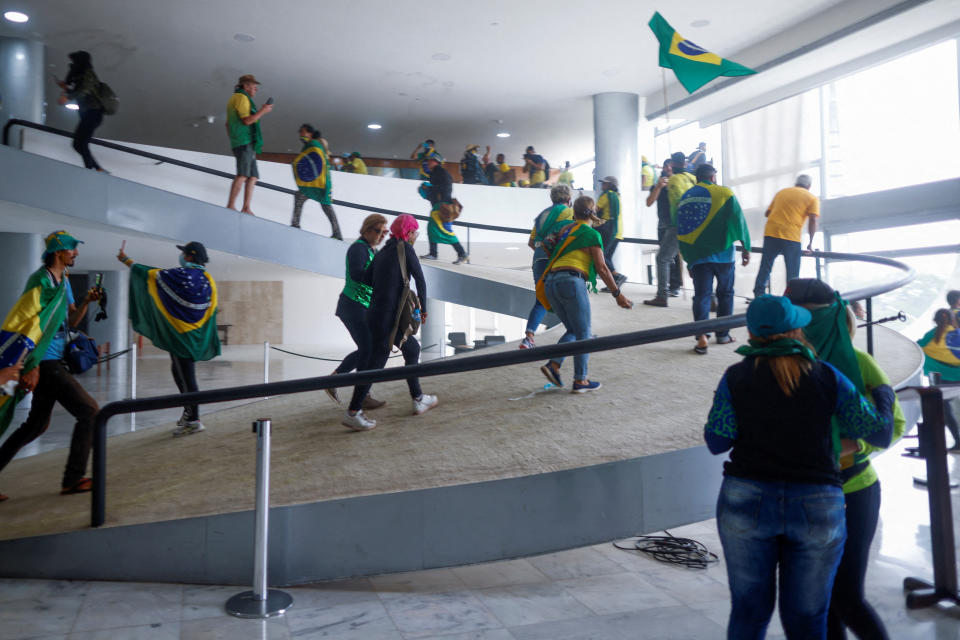 Supporters of Brazil's former President Jair Bolsonaro rush up a ramp in Planalto Palace.