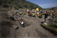 A cemetery worker digs a grave at the municipal cemetery Valle de Chalco amid the new coronavirus pandemic, on the outskirts of Mexico City, Tuesday, Oct. 20, 2020. Mexican families traditionally flock to local cemeteries to honor their dead relatives as part of the “Dia de los Muertos,” or Day of the Dead celebrations, but according to authorities the cemeteries will be closed this year to help curb the spread of COVID-19. (AP Photo/Marco Ugarte)