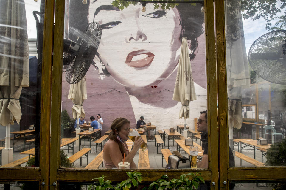 Amber Kirtley, left, and Jeff Gullo drink beers at Dacha Beer Garden in the Shaw neighborhood in Washington, Friday, May 29, 2020, as the District of Columbia gradually loosens stay-at-home rules that have been in place since March 25 because of the pandemic and allows restaurants to resume outdoor dining. (AP Photo/Andrew Harnik)