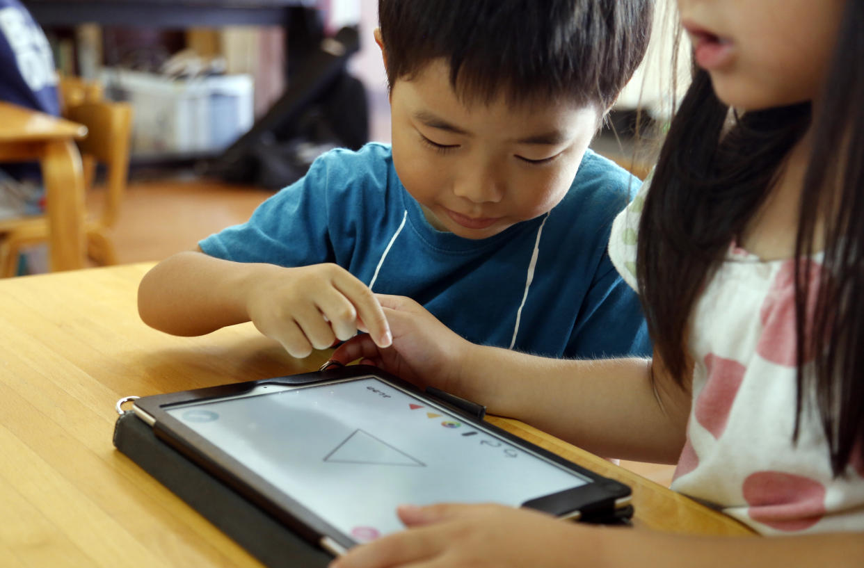 In this July 12, 2018, photo, children work on a digital program at Coby Preschool in Yoshikawa, suburban Tokyo, on an assignment, which was to draw on a triangle on an iPad. For the kids, it’s all about having fun. Japanese preschool programs equipped with tablet computers aim to prepare kids for the digital age. (AP Photo/Yuri Kageyama)