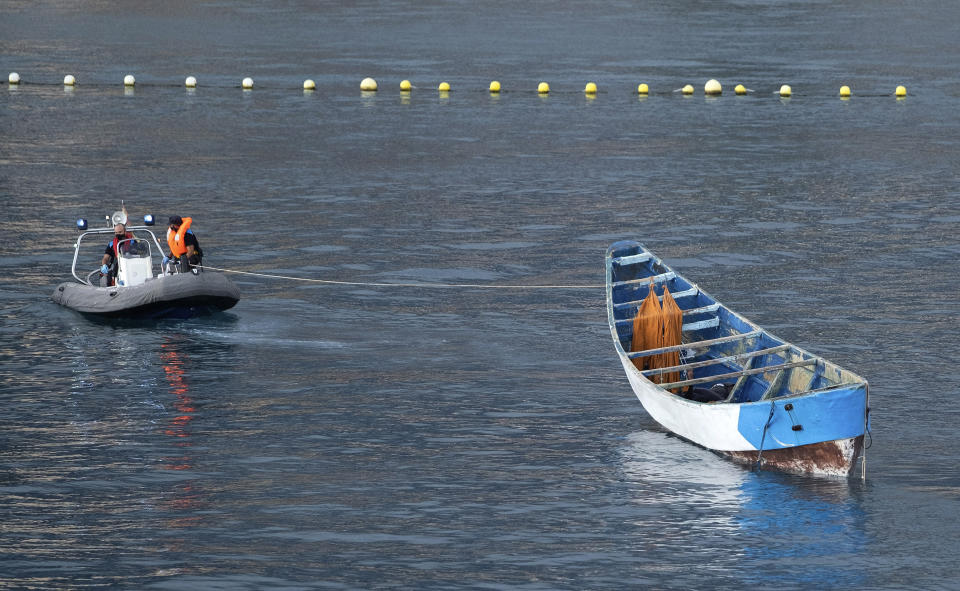 A wooden boat carrying the bodies of dead bodies of migrants is towed by emergency services as they arrive at the port of Los Cristianos in the south of Tenerife, in the Canary Island, Spain, Wednesday, April 28, 2021. Spanish authorities have brought to shore the bodies of 24 migrants from sub-Saharan Africa, among them two minors. The migrant boat was spotted on Monday by a Spanish military plane 265 nautical miles from the island of El Hierro, three survivors were airlifted, the others are believed to have died from thirst and hunger during the perilous migratory journey from the West coast of Africa to the Canary Islands. (AP Photo/Andres Gutierrez)