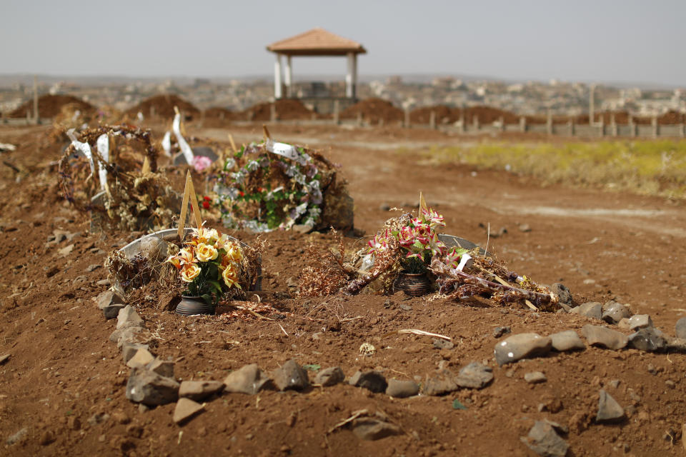 In this Thursday, Oct. 4, 2018, photo, graves of 20 Druze men, who were killed three months ago during a stunning Islamic State attack, are covered by flowers in the village of Rami in the southern province of Sweida, Syria. Three months after a stunning Islamic State attack on a southeastern corner of Syria in which more than 200 people were killed and 30 women and children abducted, tensions are boiling over, and young men are taking up arms. It is a stark change for a province that managed to stay on the sidelines of the seven-year Syrian war and where most villagers worked grazing livestock over surrounding hills. (AP Photo/Hassan Ammar)