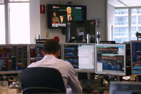 A trader works at his desk as the U.S. presidential town hall debate between Republican presidential nominee Donald Trump and Democratic nominee Hillary Clinton is shown on television at Citibank's trading floor located in central Sydney, Australia, October 10, 2016. REUTERS/David Gray