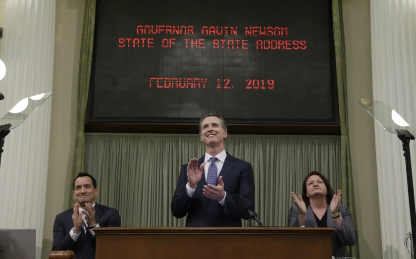 California Gov. Gavin Newsom, center, flanked by Assembly Speaker Anthony Rendon, D-Lakewood, left, and Senate President Pro Tem Toni Atkins, D-San Diego, right, applauds Camp Fire survivor Allyn Pierce during his first state of the state address to a joint session of the legislature at the Capitol Tuesday, Feb. 12, 2019, in Sacramento, Calif. Newsom praised Pierce, who survived the flames of the Camp Fire last fall and began treating patients at a hospital in Paradise when he could have fled from the Sierra Nevada foothills community. (AP Photo/Rich Pedroncelli)